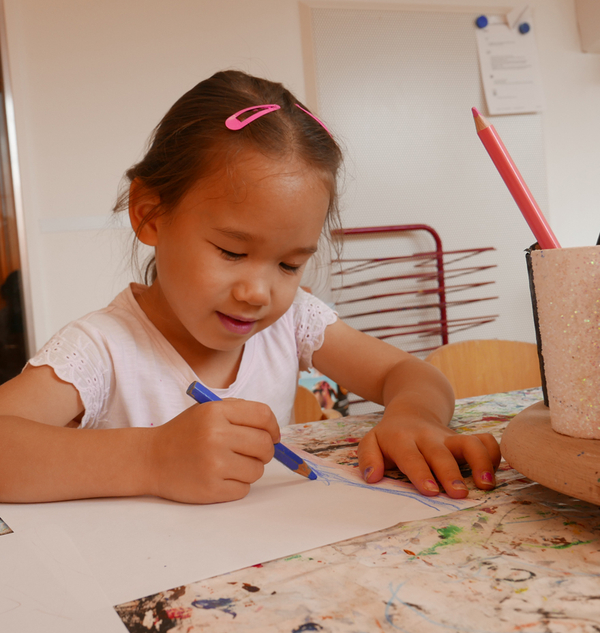 Bild Siloah Kindertagesstätten, Kindergartengruppen, Mädchen sitzt am Tisch und malt ein Bild 